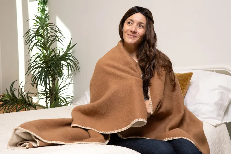 A woman wrapped in the twin blanket on a bed