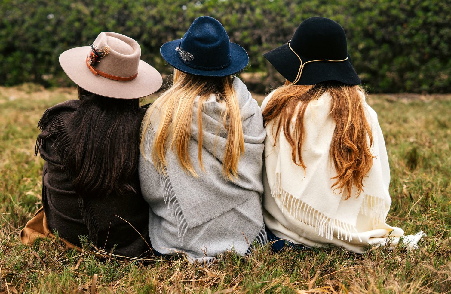 Three women sitting in a field in Peru, wrapped in Andean, Sterling and Natural baby alpaca throws